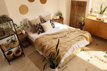 Interior of cozy bedroom with plants, shelf unit and commode
