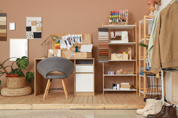 Interior of fashion designer's studio with workplace, shelf units and palm tree