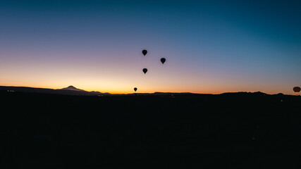 Cappadocia with colorful hot air balloons flying in the sky over deep canyons .