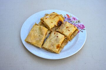 Freshly baked appetizing Turkish tortillas - Gozleme with spinach, cheese  on a white board. Space for text. Handmade Turkish traditional pastries. Ispanakli, otlu peynirli gozleme. Tahinli Katmer