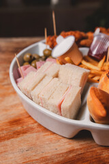 Close-up view of small ham and cheese sandwiches, along with different snacks on a tray.