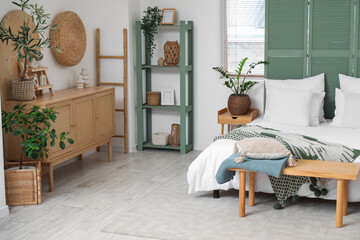 Stylish interior of bedroom with shelving unit and bench