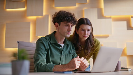 Frustrated colleagues reading email at laptop coworking at office closeup.