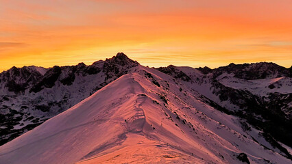 Naklejka premium Kasprowy Wierch o zachodzie słońca z ośnieżonym grzbietem górskim.