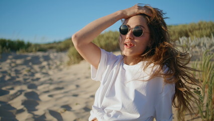 Summer woman enjoying wind at beach portrait. Young relaxed lady touching hair