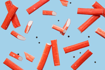 Tasty crab sticks and peppercorns flying on blue background © Pixel-Shot