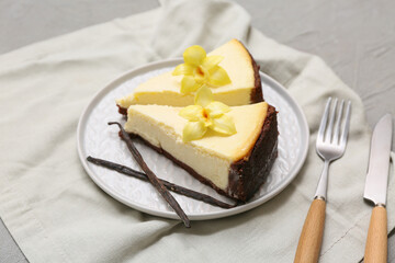 Plate with pieces of sweet vanilla cheesecake on grey background