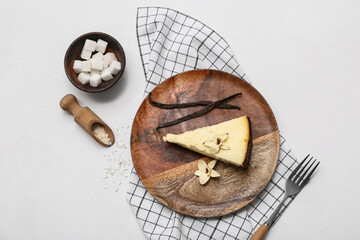 Wooden plate with piece of sweet vanilla cheesecake and bowl of sugar cubes on white background