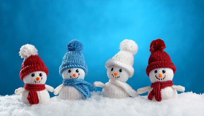 little knitted snowmans on soft snow on blue background