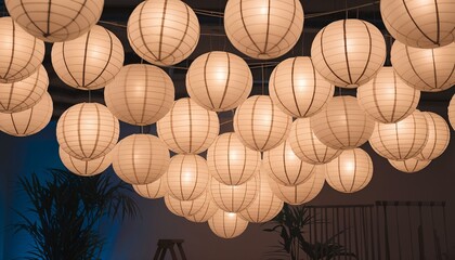 Glowing paper lanterns creating a dreamy atmosphere in a dark room with plant and ladder