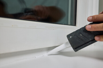 Sealing the corners of windows with caulk for achieving a perfectly neat and polished finish