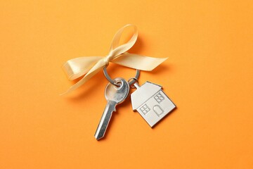 Metallic key with keychain in shape of house on color background