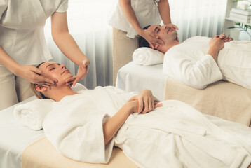 Obraz premium Caucasian couple enjoying relaxing anti-stress head massage and pampering facial beauty skin recreation leisure in dayspa modern light ambient at luxury resort or hotel spa salon. Quiescent