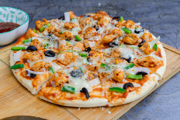 Freshly sliced B.B.Q pizza with olives, mozzarella, and chicken on a rustic plate with sauce
