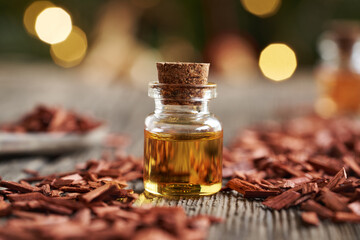 A transparent bottle of essential oil with red sandalwood chips