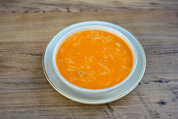 Homemade turkish soup Tavuk Suyu corbasi in a white ceramic soup plate.Turkish noodle chicken broth soup on a plate. Turkish meal (sehriyeli tavuk suyu corbasi). Ezo Gelin Corbasi. Islkembe, corbasi