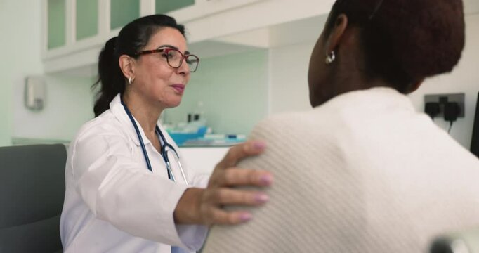 Kind mature doctor touches female shoulder, provides psychological support while talking about further operation, share good news, disease recovery, effective treatment, encouraging supporting patient
