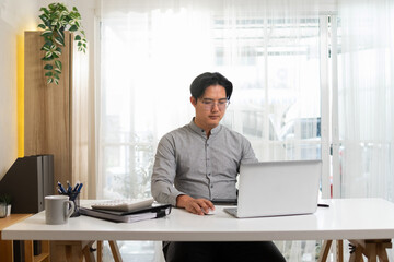 young man working in room white wooden work desk and work equipment on the table