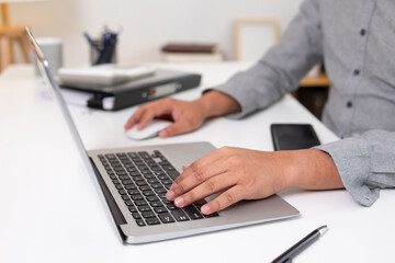 Young man uses his hand to touch a laptop on his desk.