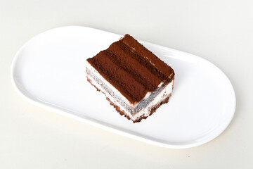 Perfect homemade tiramisu cake with fresh mint. Tiramisu portion on plate over gray background. Delicious no bake tiramisu ready-to-eat. Close up. Copy space