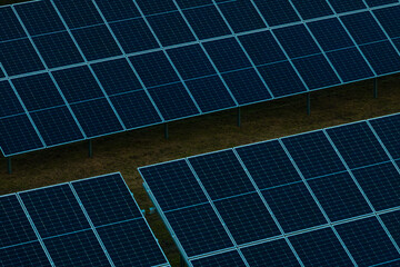 Grid like arrangement of solar panels on metal supports above grass covered ground, designed for...