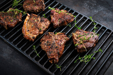 Authentic barbecued T-Bone lamb steak with thyme served as close-up on a rustic grillage