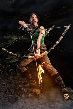 Portrait of screaming woman adventurer with a bow and burning arrow