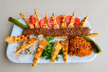 Grilled Turkish Adana, Urfa  Kebab with grilled vegetables, onion and rice on plate. Urfa, Adana durum.
