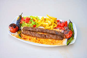Grilled Turkish Adana, Urfa  Kebab with grilled vegetables, onion and rice on plate. Urfa, Adana durum.
