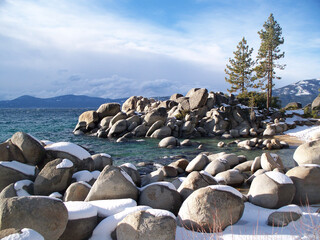 Snow-covered boulders in winter line the shore at Sand Harbor State Park, Nevada.