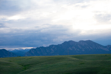 Fototapeta premium Green rolling hills with mountains in the distance