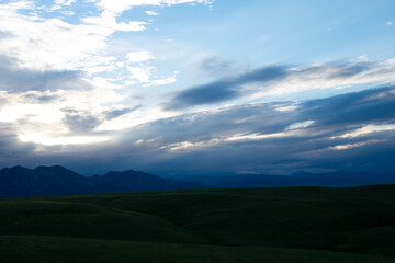 Green rolling hills with mountains in the distance