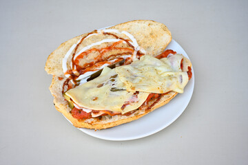Close-up shot of Izmir's famous Turkish Traditional Kumru Sandwich, Ceşme Kumru, patso ingredients ready to eat salami, soudjouk, tomato, cheddar cheese and fried cheese. Yengen sandvic. Izmir karisik