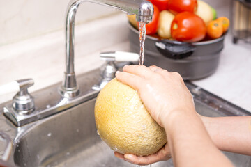 Woman washing organic melon, food disinfection concept