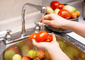 Woman washing organic tomatoes, food disinfection concept