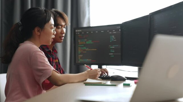 Slow motion back end software developer engineer for computer programming working together on debugging writing computing code, solving complex algorithms display on monitor in office. Burgeoning
