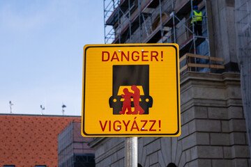 Street sign in Budapest, Hungary with an image of two people looking at their cell phones walking in front of a truck, with the text Danger, Vigyazz!
