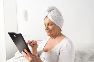 Caucasian senior woman with wrinkles talking with somebody by tablet