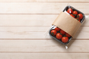 Pack of fresh tomatoes on wooden table, top view. Space for text