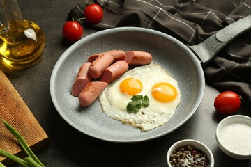 Tasty fried eggs and sausages served on grey table, closeup