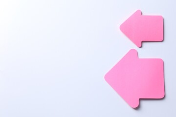 Pink paper arrows on white background, flat lay. Space for text