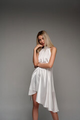 Portrait of a beautiful girl in a white dress on a gray background