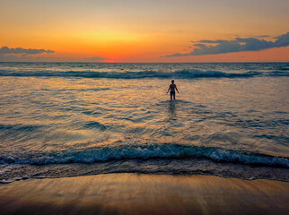 woman in surf at sunset