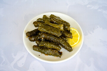 Delicious dolma (sarma) stuffed grape leaves rice, white yogurt sauce. Lebanese dolma sarma on plate. Lebanon turkish greek middle eastern cuisine. (Turkish name; yogurtlu yaprak sarma)