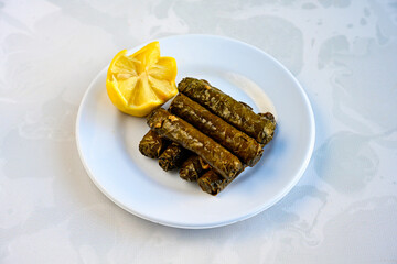 Delicious dolma (sarma) stuffed grape leaves rice, white yogurt sauce. Lebanese dolma sarma on plate. Lebanon turkish greek middle eastern cuisine. (Turkish name; yogurtlu yaprak sarma)