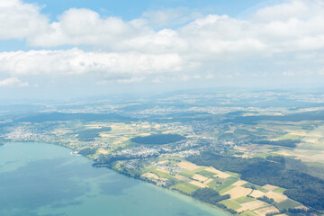 Aerial View of a Lake Bordered by Fields and Forests under a Cloudy Sky, Switzerland