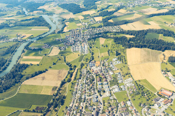 Houses along a river from a aerial drone view surrounded by farming land, Switzerland
