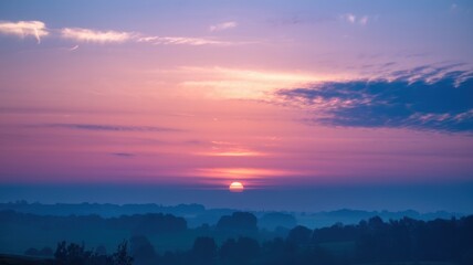 Obraz premium A breathtaking sunset painting the sky in hues of purple and orange over a misty landscape, creating a tranquil and serene atmosphere.