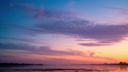 Obraz premium A serene sunset over calm waters, featuring a blend of vibrant pink, orange, and blue hues in the sky, creating a tranquil atmosphere.