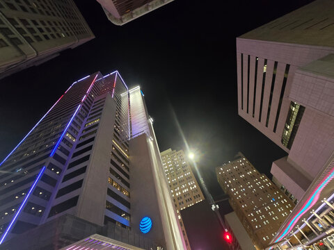 The ATT Building surrounded by skyscrapers and hotels at the AT and T Discovery District with colorful lights at night  in downtown Dallas Texas USA